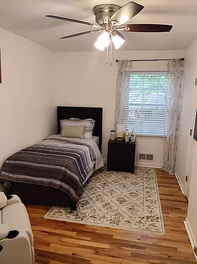 Home A resident bedroom with a made bed, window and ceiling fan